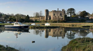 Laugharne Castle with a small boat in front